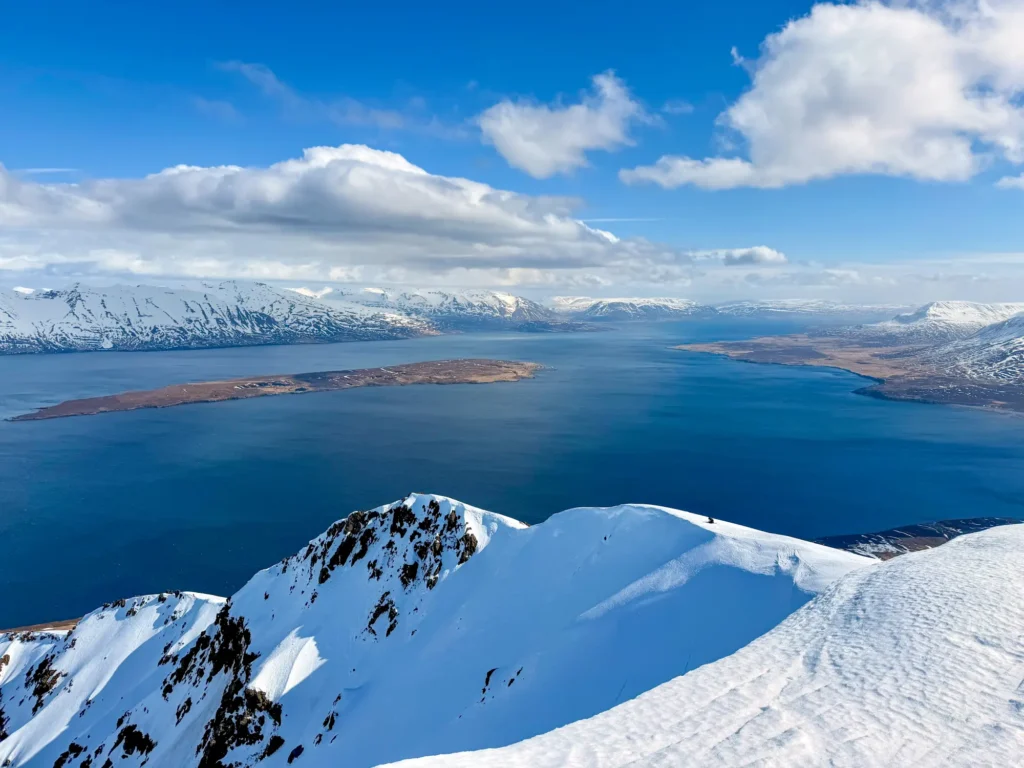 Ski touring in Iceland. A ski tourer in the foreground, behind them the blue fjord